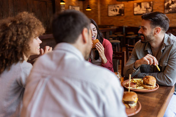 istock Friends Laughing and Eating Fast Food at Pub 2230468907