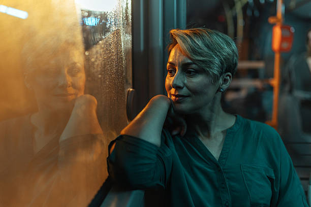Woman reflecting by a bus window at night