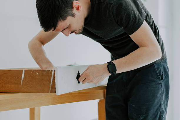 A young man repairs a retro handle on a drawer.