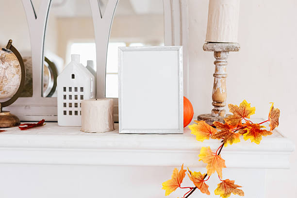 istock Decorative mantelpiece with blank picture frame and autumn elements arranged in cozy interior 2230488399
