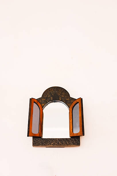 istock Reflective wooden mirror with decorative details set against a plain background 2230488401