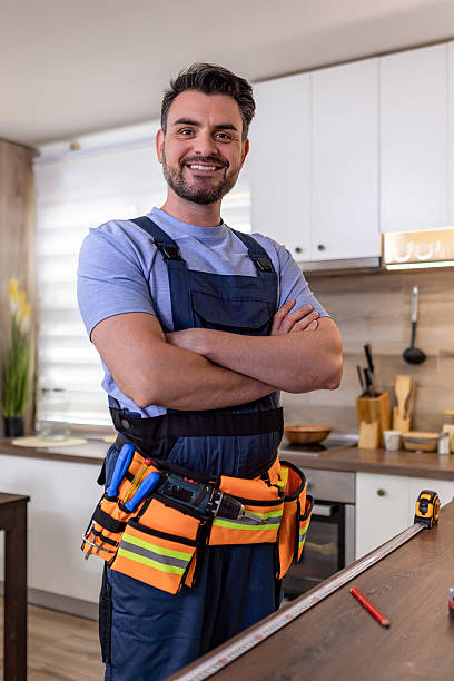 istock Skilled worker in blue overalls with tools standing confidently in a modern kitchen 2230490319