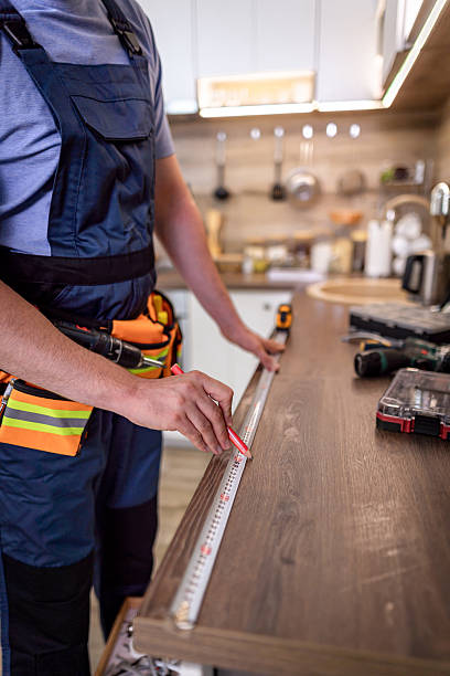 istock Craftsman measures wooden countertop in modern kitchen for precise installation during renovation 2230490335