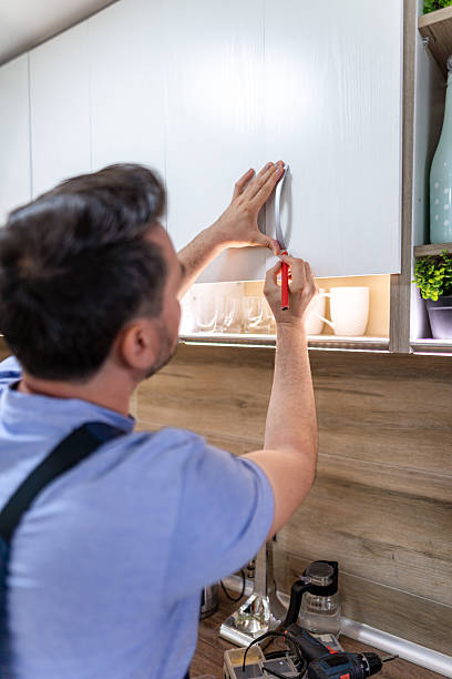 istock Man installs cabinet handles in a modern kitchen during a home improvement project 2230490383
