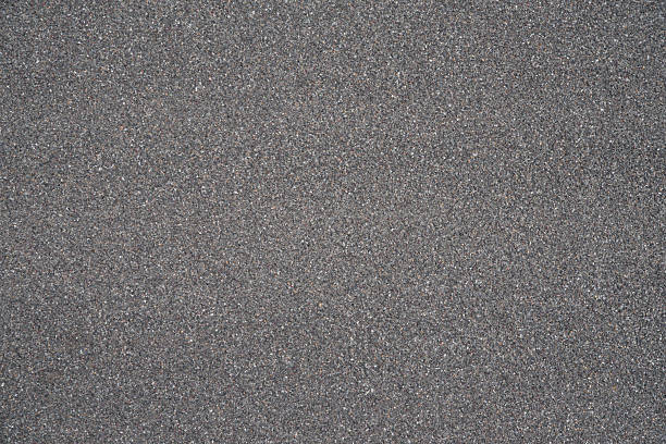 Seamless uniform dark gray stone granules texture, gravel aggregate surface background