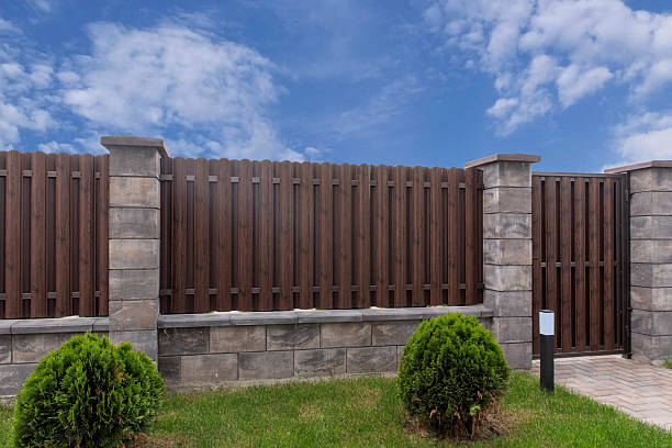 Metal picket fence with stone columns and wooden texture gate