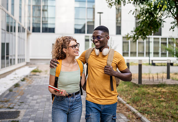 istock Two happy students walking and talking outdoors 2230498706