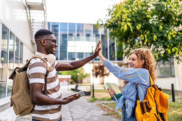 istock Happy students giving high five outdoors 2230499654