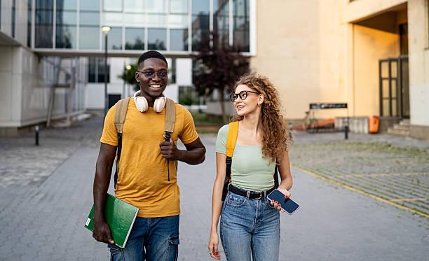 istock Smiling students walking and talking outdoors 2230499936