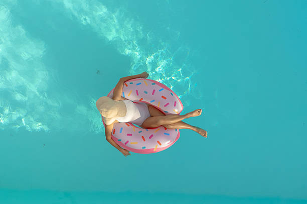Lady enjoying the pool with inflatable swim ring from drone