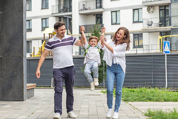 istock Happy parents swinging son while walking outside. Back to school 2230515577