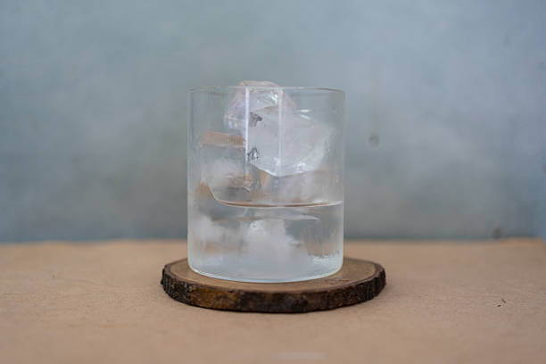 Glass of water with ice cubes on a wood table