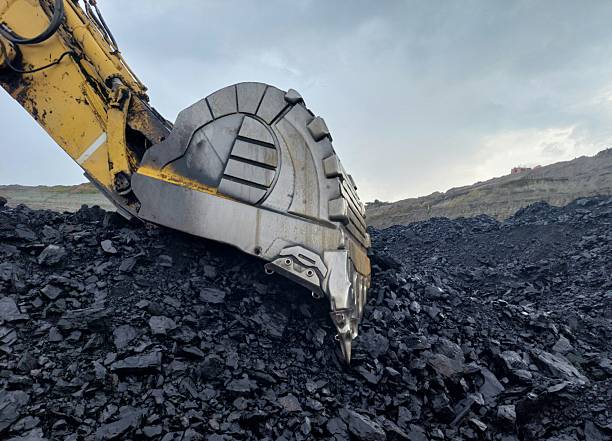 Bucket from a large excavator used to load coal into a dump truck vessel in a open-pit coal mine.