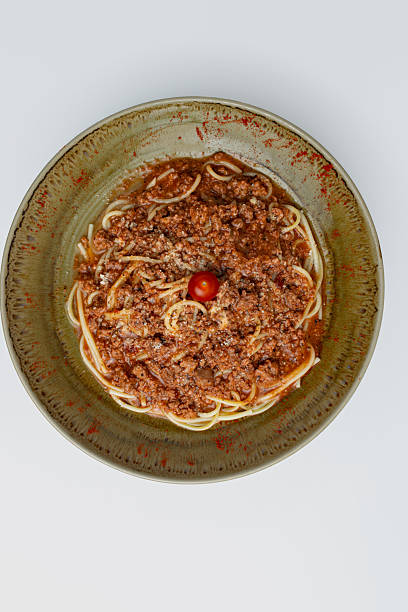 Gourmet Spaghetti Bolognese with a rich meat sauce (ragu) and Parmesan cheese, a classic Italian pasta dish served for dinner as a main course in a rustic bowl, isolated on a white background.