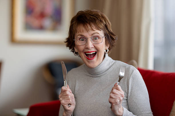Happy woman at home with knife and fork