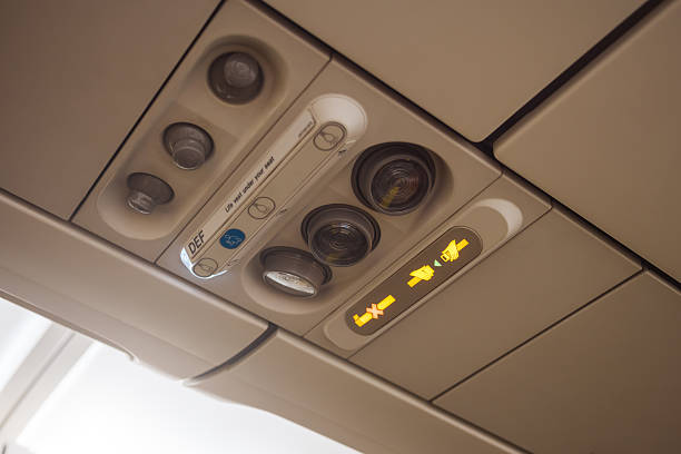 Close-up of an aircraft overhead panel showing illuminated seatbelt and no smoking signs along with air vents and light buttons. Ideal for airline safety, travel editorials, and aviation content.