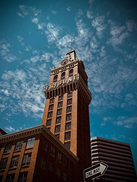 Red brick tower with dramatic top against blues skies with puffy clouds.