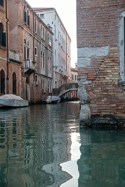 a narrow canal in Venice, Italy, between colorful historic buildings, during a sunny day, offering a glimpse of Venetian life