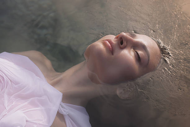 istock Woman Floating Peacefully In Water With Closed Eyes And Soft Sunlight Glow 2230546128