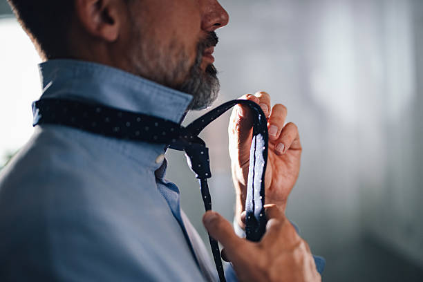 A close-up view of a man tying his polka dot tie, showcasing professionalism and personal grooming in a well-lit modern environment, emphasizing preparation and style for business or social settings.