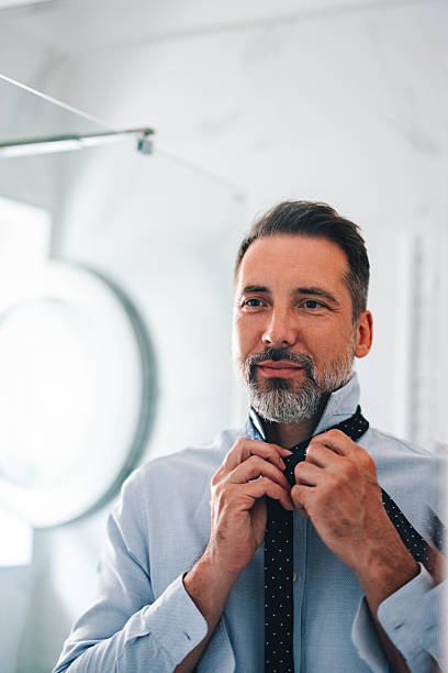 istock Confident Businessman Adjusting His Tie in a Bright Modern Office Setting 2230547042
