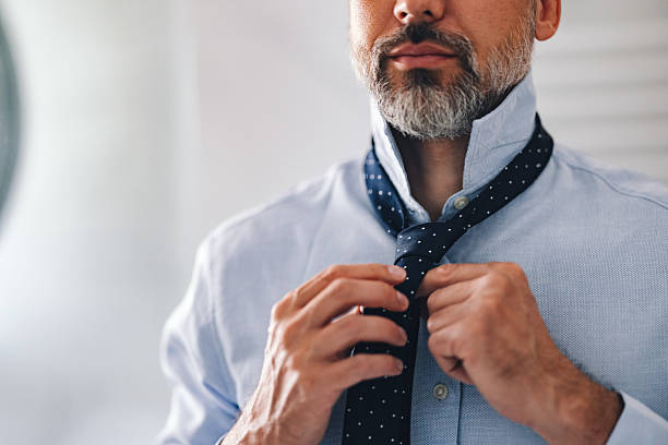 istock Man Adjusting Tie in Office Attire Ready for Formal Event or Business 2230547050