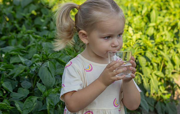 istock little girl drinking water on a nature background. Selective focus 2230550118