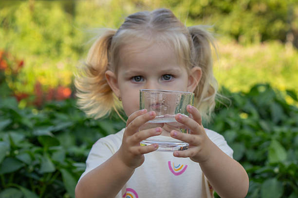 istock little girl drinking water on a nature background. Selective focus 2230550129