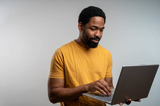 istock Confident male entrepreneur analyzing report over laptop while standing over white background 2230551015