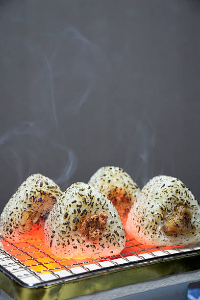 Grilling rice balls on a charcoal grill with smoke rising