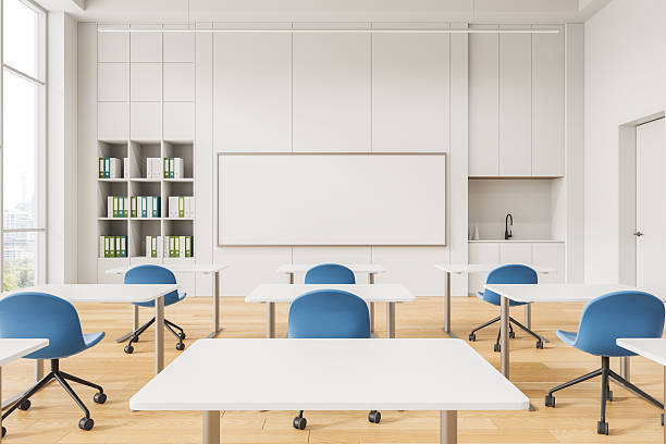 istock Modern minimal classroom with blue chairs, white desks, large whiteboard, storage shelves, and wooden floor in bright, clean educational interior design. 3D Rendering 2230553016