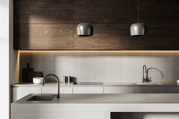 istock Modern minimalist kitchen interior with light concrete island, wood cabinets, and pendant lighting under warm strip light in neutral tones. 3D Rendering 2230553387
