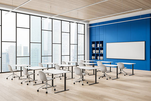 istock Modern classroom interior with white desks, chairs, and large whiteboard in front of blue wall and panoramic windows overlooking cityscape. 3D Rendering 2230553504