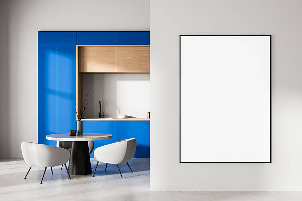 istock Modern interior with blue kitchen cabinets, minimalist dining area, and large empty framed poster on clean white wall for design presentation mockup. 3D Rendering 2230553523