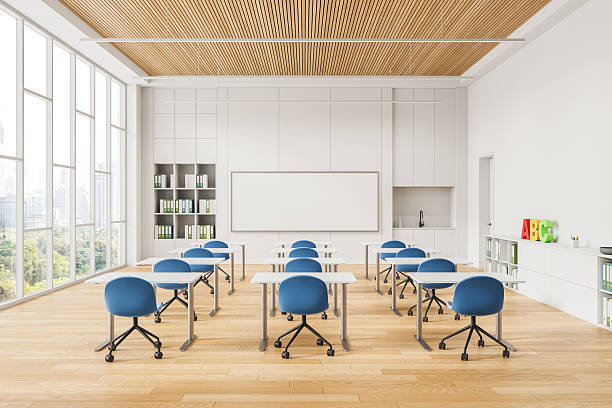istock Modern classroom interior with blue chairs, white desks, wooden ceiling, and large whiteboard in bright educational space concept design setup. 3D Rendering 2230553542