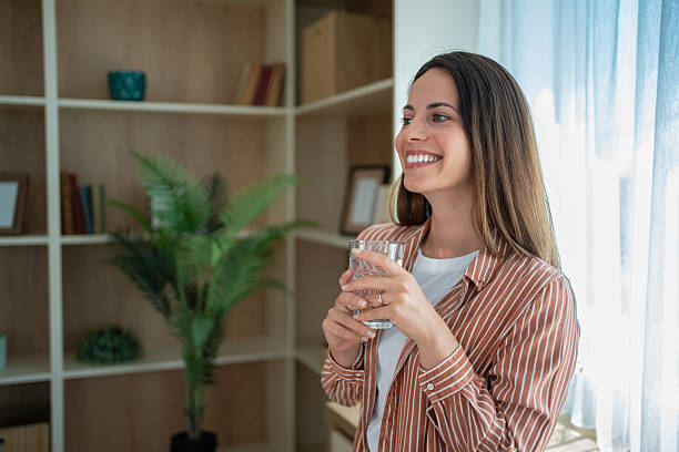 istock Young woman drinking water and smiling at home 2230557997