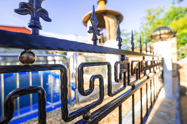 istock A black wrought iron fence with a blue pool in the background 2230572986
