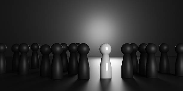 istock 3D render of a shiny white doll standing apart from matte black dolls, representing individuality, leadership, uniqueness, success, innovation, and standing out from the crowd. 2230576423