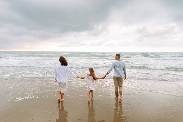 istock Young family expecting baby spend time together on seashore. 2230576848