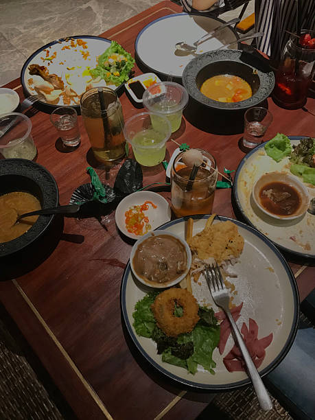 Dining table with assorted dishes, side dishes, sauces, and colorful drinks after meal, showing casual dining atmosphere indoors