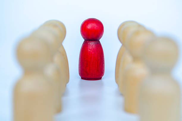 istock A red figure separated with a visible gap from wooden figures, representing leadership or isolation or discrimination concept 2230580144