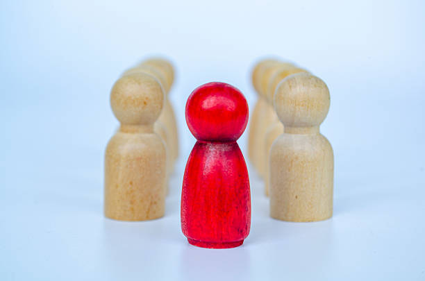 istock A red figure in front of wooden figures symbolizing leadership or authority or influence concept 2230580146