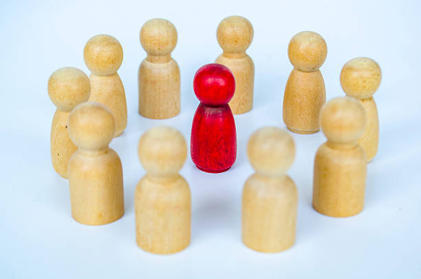 istock A red figure surrounded by wooden figures in a circle, representing inclusion and equity or harassment or leadership concept 2230580446