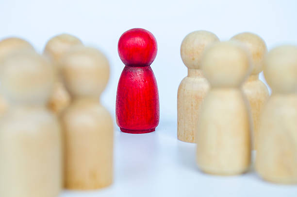 istock A red figure surrounded closely by wooden figures in an intense manner, representing leadership or bullying or harassment concept 2230580496