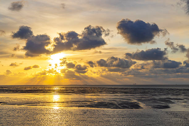 Sunset over a beach with a stranded sailing boat.