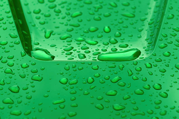 Raindrops on smooth green metallic industrial object surface, weather and climate concept, selective focus