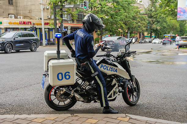 Almaty, Kazakhstan - July 14, 2025: A policeman on a motorcycle holds a smartphone in his hands. Public safety