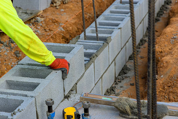 istock Construction worker lays concrete blocks at building site in broad daylight, ensuring precise alignment stability 2230589900