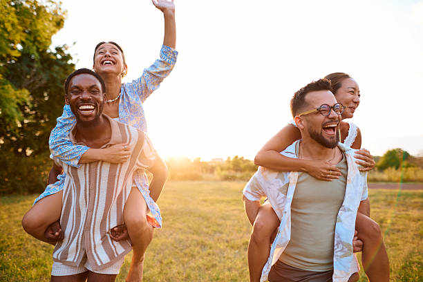 istock Two happy couples having fun piggybacking in a park at sunset 2230591547