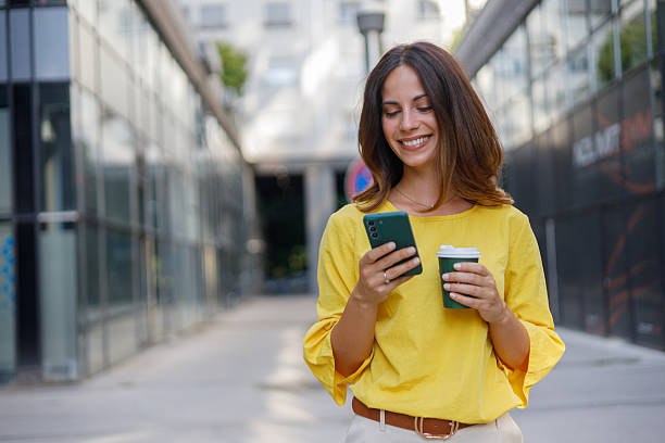 istock Professional woman navigating urban landscape, sipping coffee while texting on smartphone during morning commute 2230596980